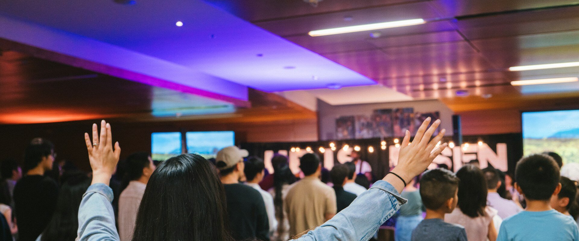 Congregación con manos alzadas en adoración a Dios